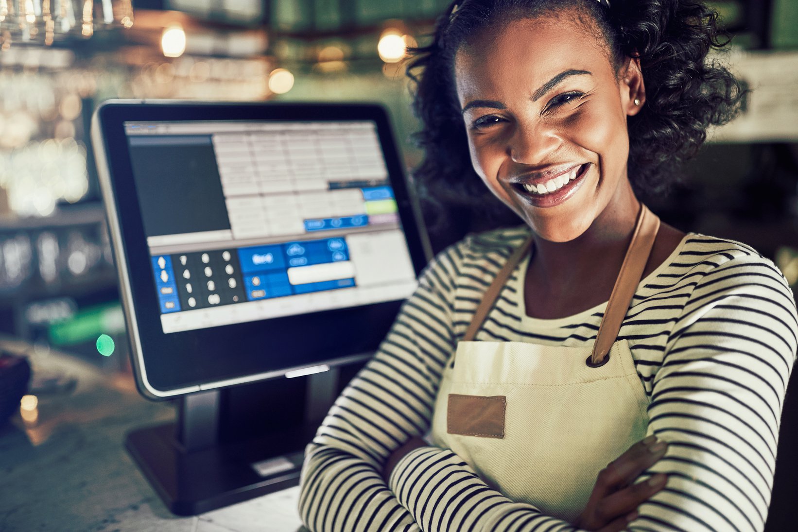 Smiling Waitress Standing by a Restaurant Point of Sale Terminal